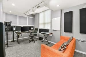 Music production studio with Yamaha studio monitors, microphones, midi keyboard, and couch