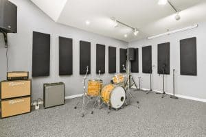 Fully backlined music practice and band rehearsal studio with drumset, amps, PA system, and sound treatment