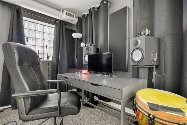 Desk with studio monitors, chair, monitor and drum.