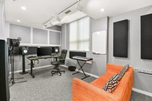 Music production studio with Yamaha studio monitors, microphones, midi keyboard, and couch
